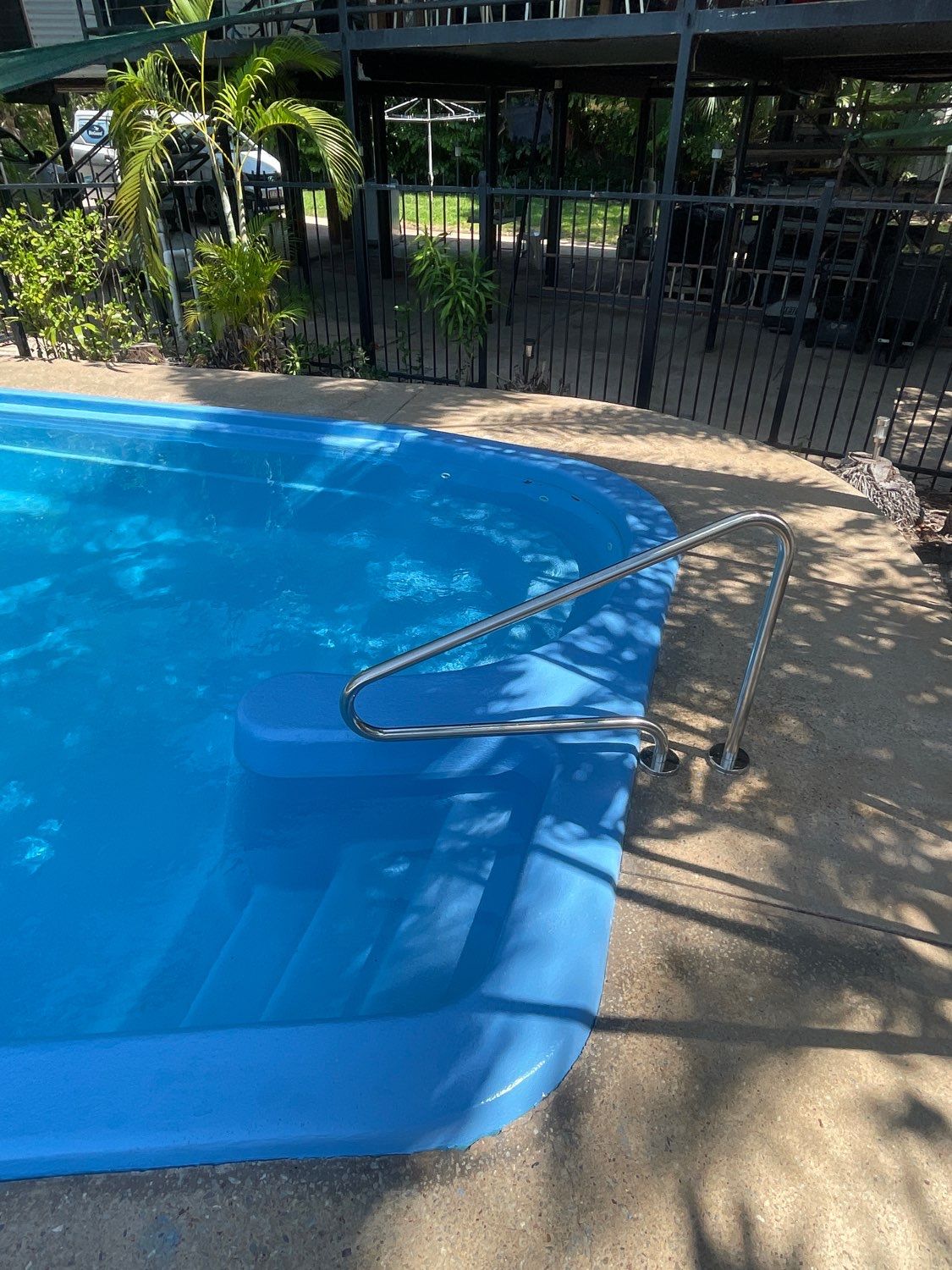 Swimming pool with blue water and steps, stainless steel handrail, outdoor setting  — Friendly Pool & Spa Care in Yarrawonga, NT 