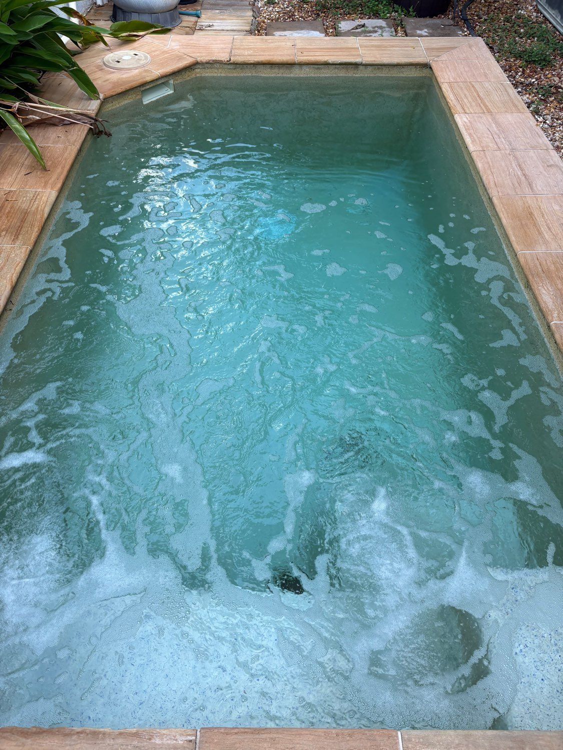 A small, rectangular jacuzzi with bubbly turquoise water, surrounded by beige stone   — Friendly Pool & Spa Care in Coconut Grove, NT 