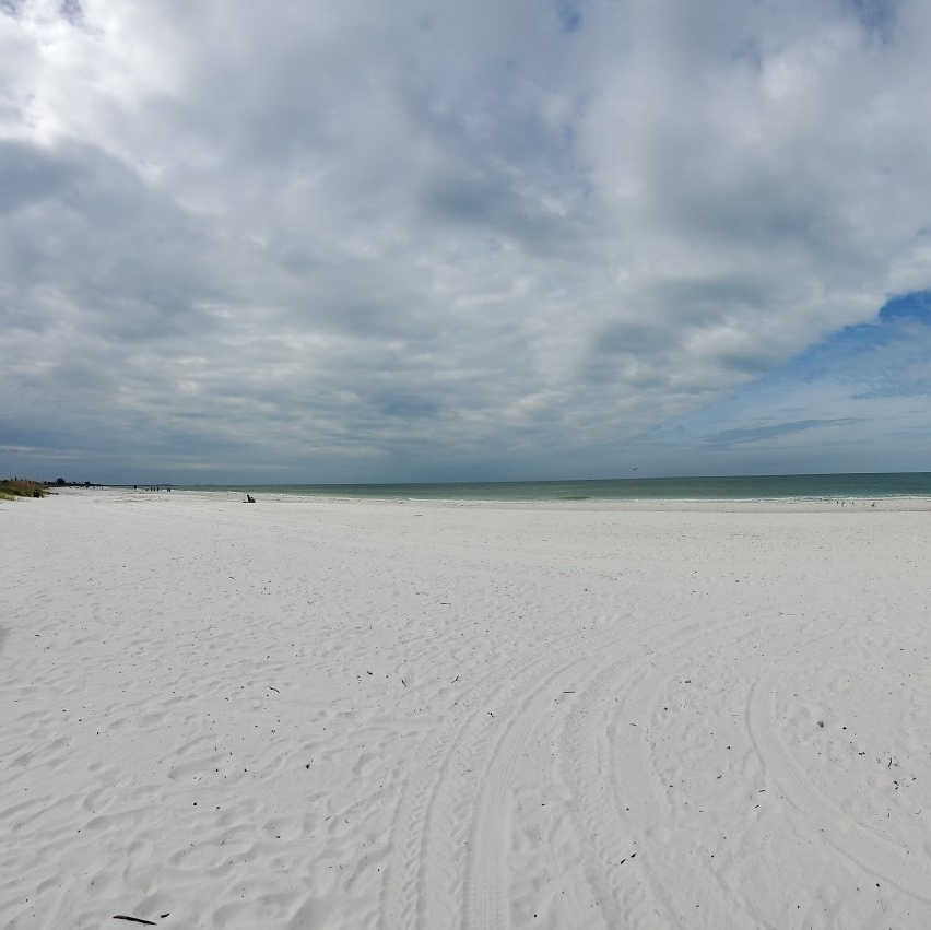 A white sandy beach with a cloudy sky in the background