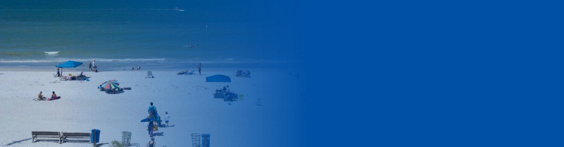 A blurry picture of a beach with people and umbrellas.