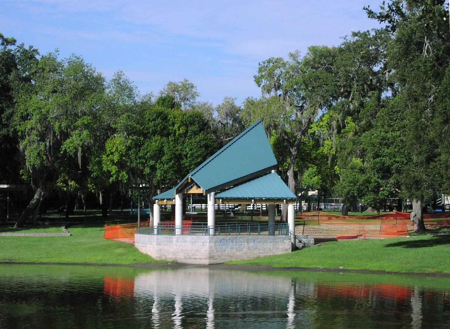 A gazebo in the middle of a park next to a lake