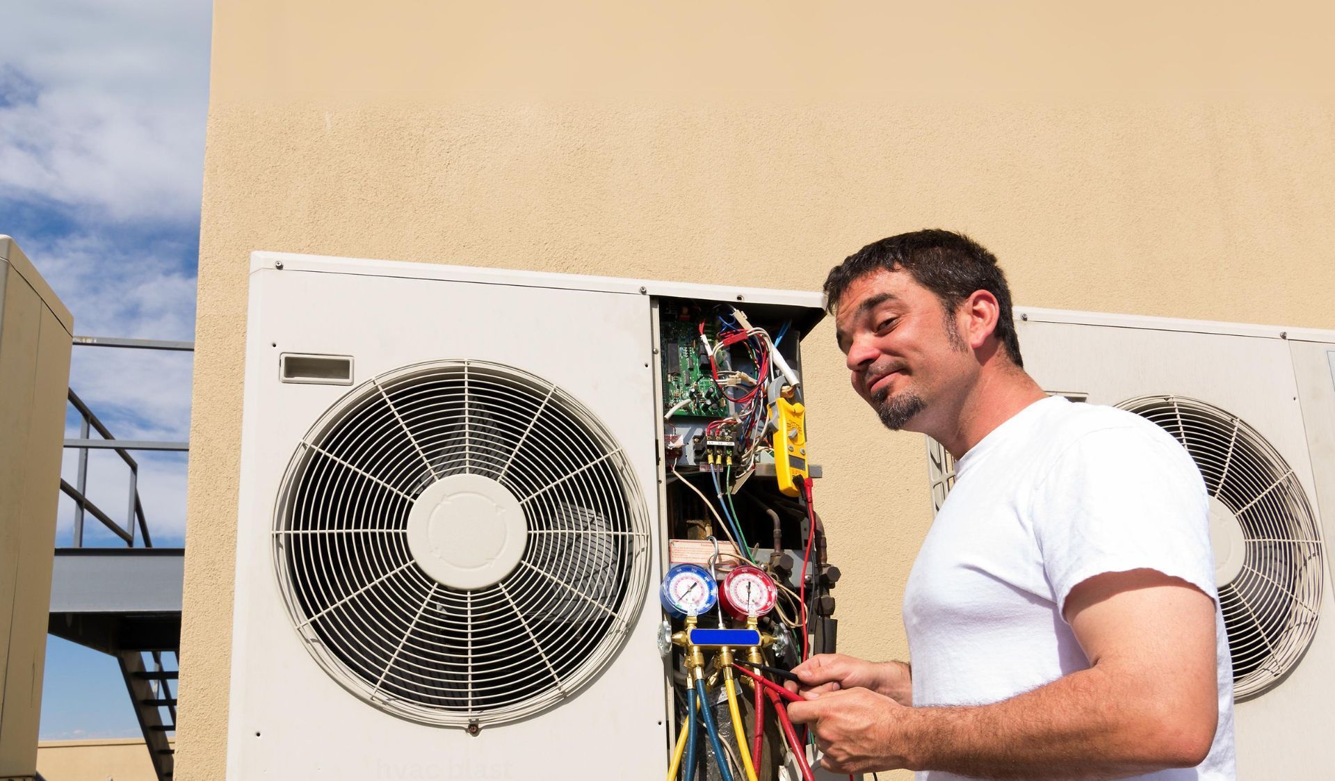 A man is working on an air conditioner outside of a building.