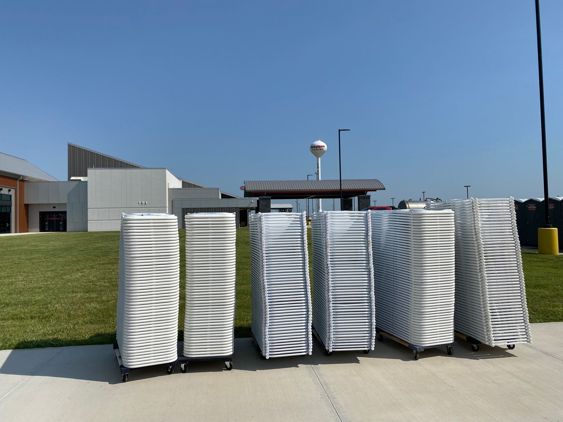 a bunch of white chairs are stacked on top of each other on a sidewalk .