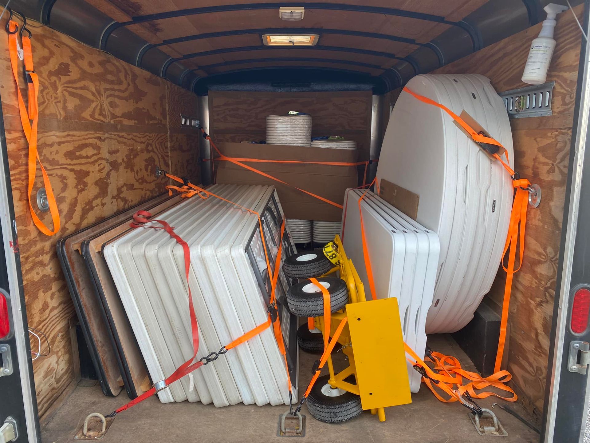 a trailer filled with tables and a yellow cart .