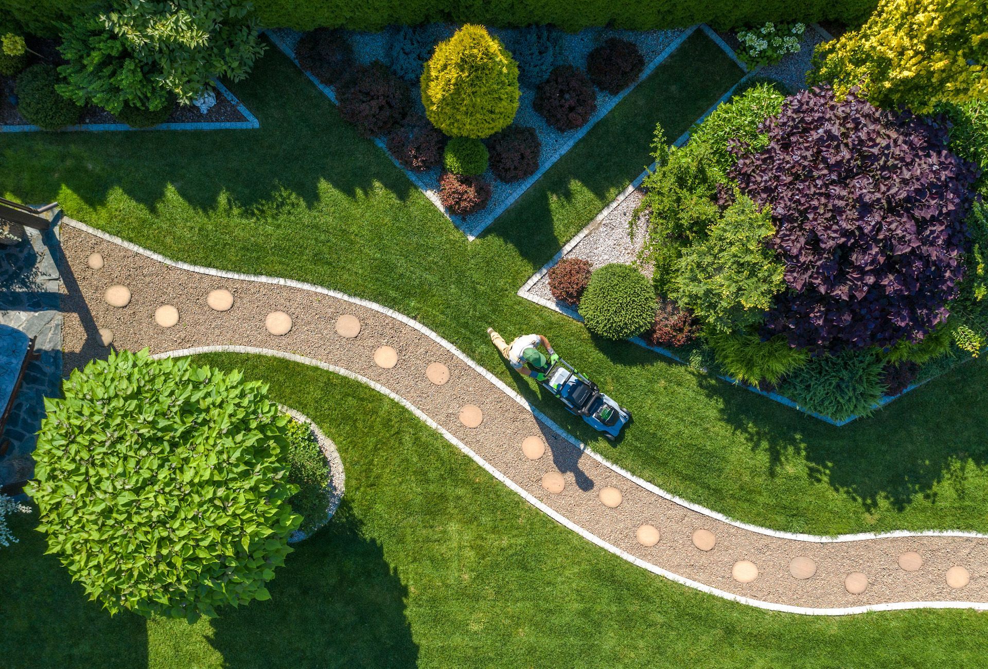 An aerial view of a person mowing a lush green lawn