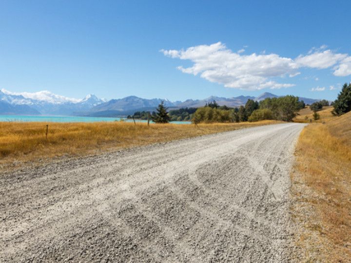 A dirt road leading to a lake with mountains in the background