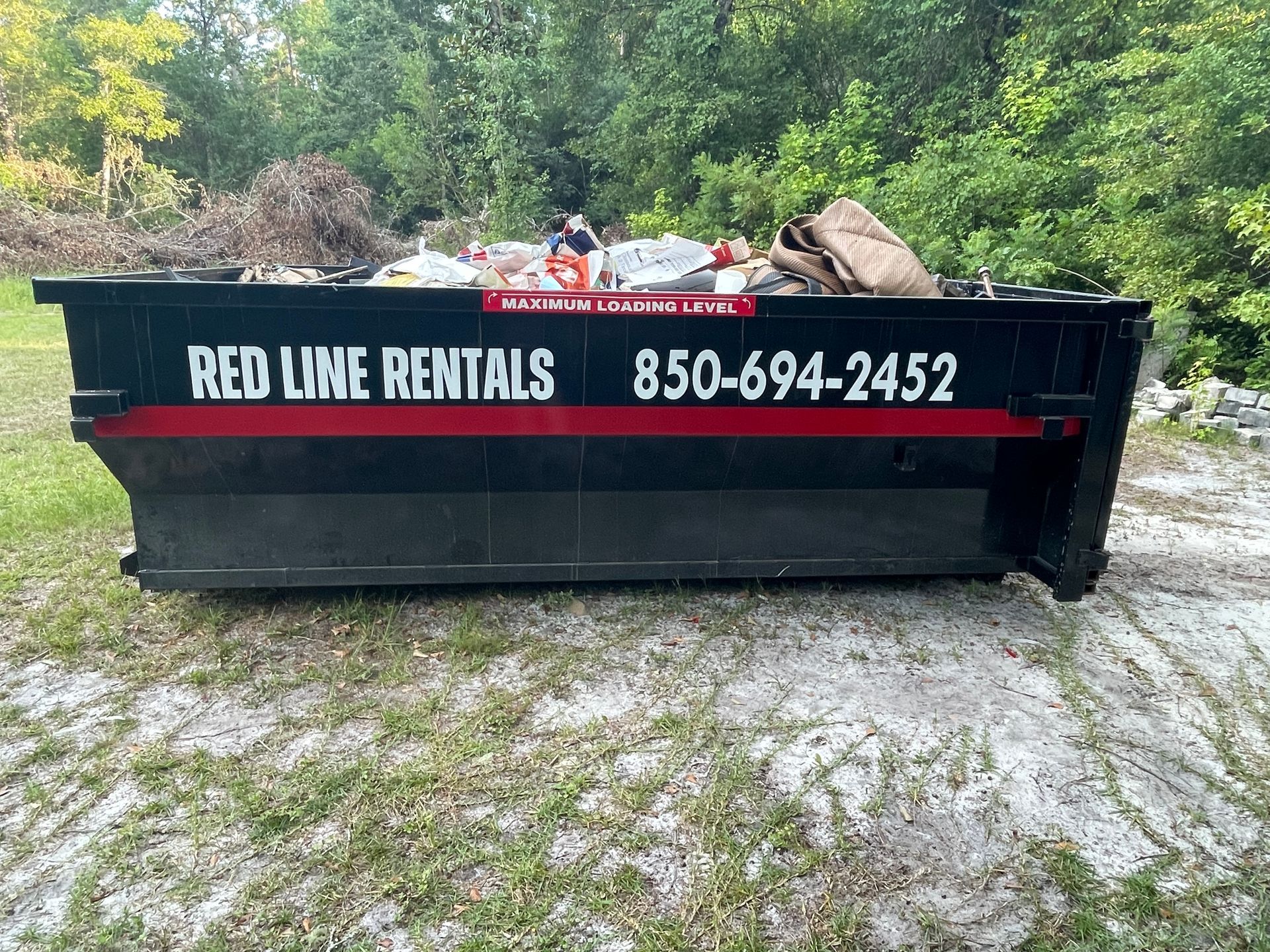 A dumpster filled with trash is sitting on the ground.
