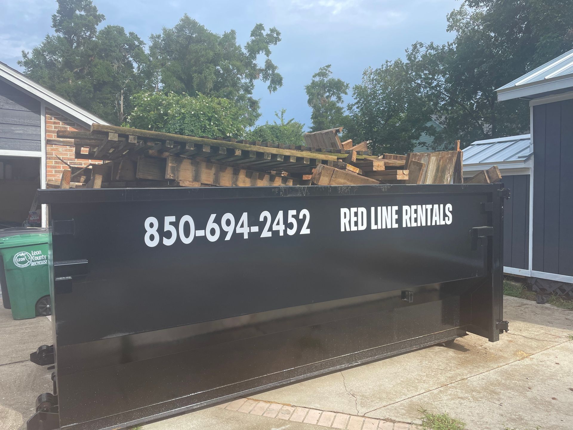 A dumpster for red line rentals is sitting in front of a house.