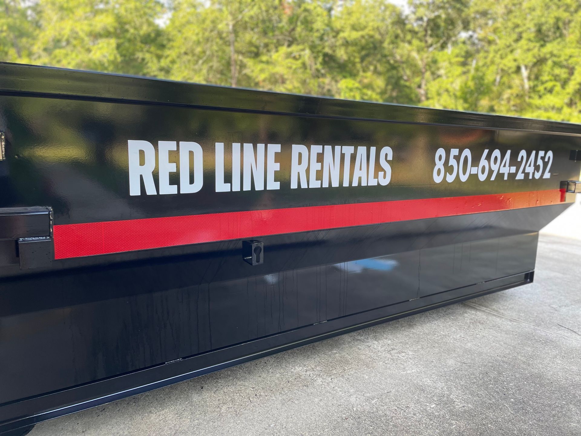 A dumpster for red line rentals is parked on the side of the road.