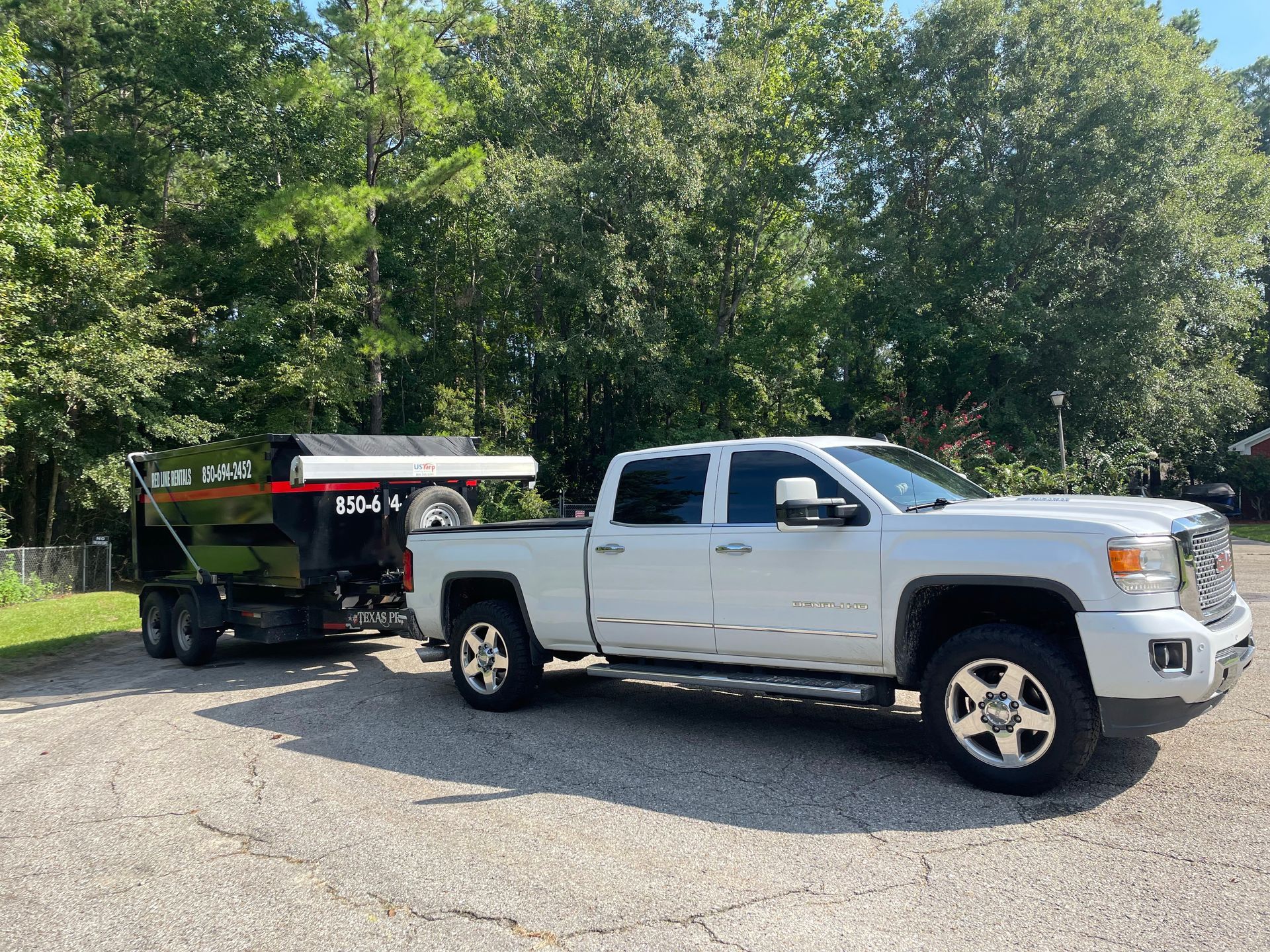 A white truck with a trailer attached to it is parked in a driveway.