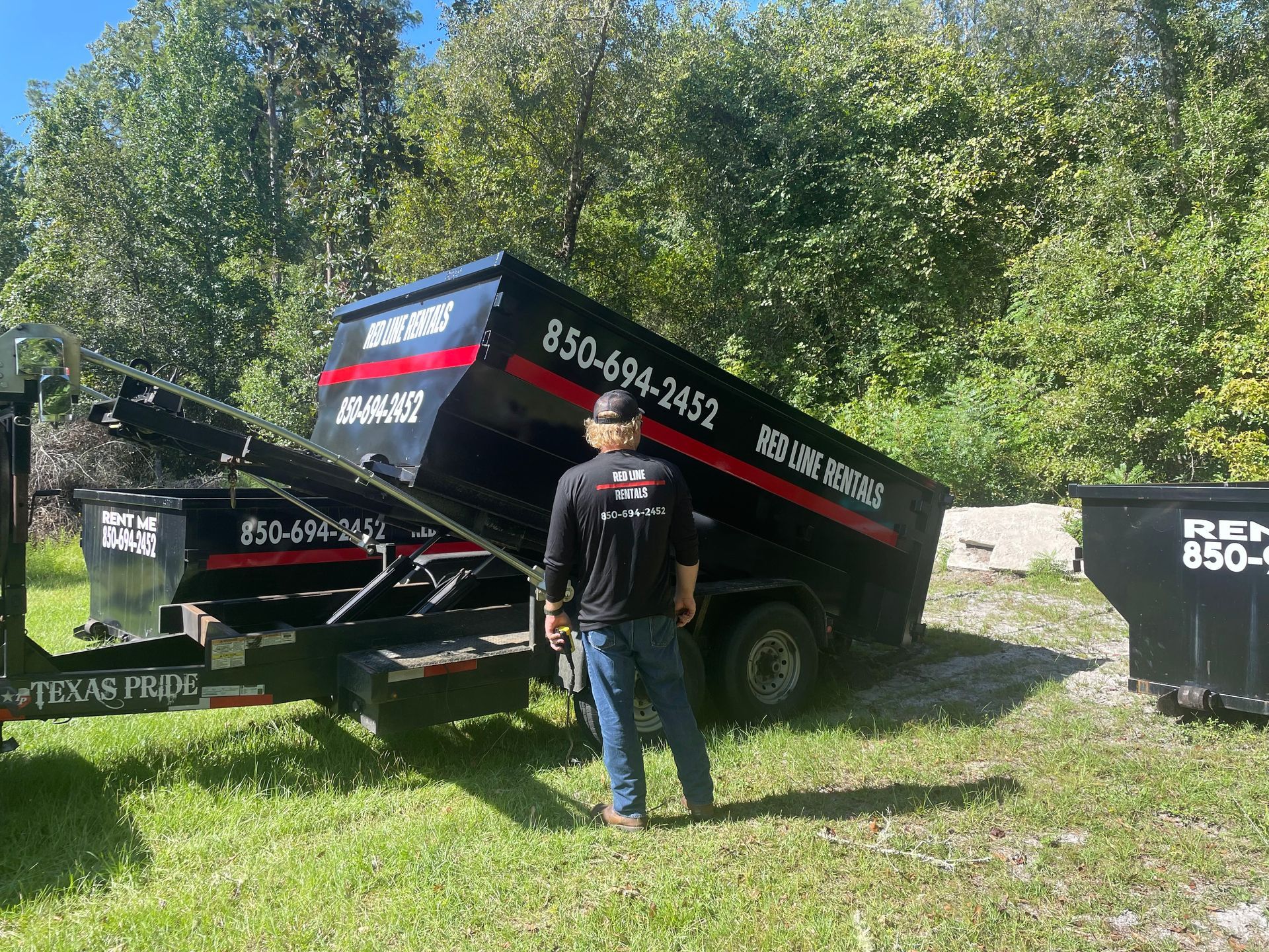 A man is standing in front of a dumpster trailer.