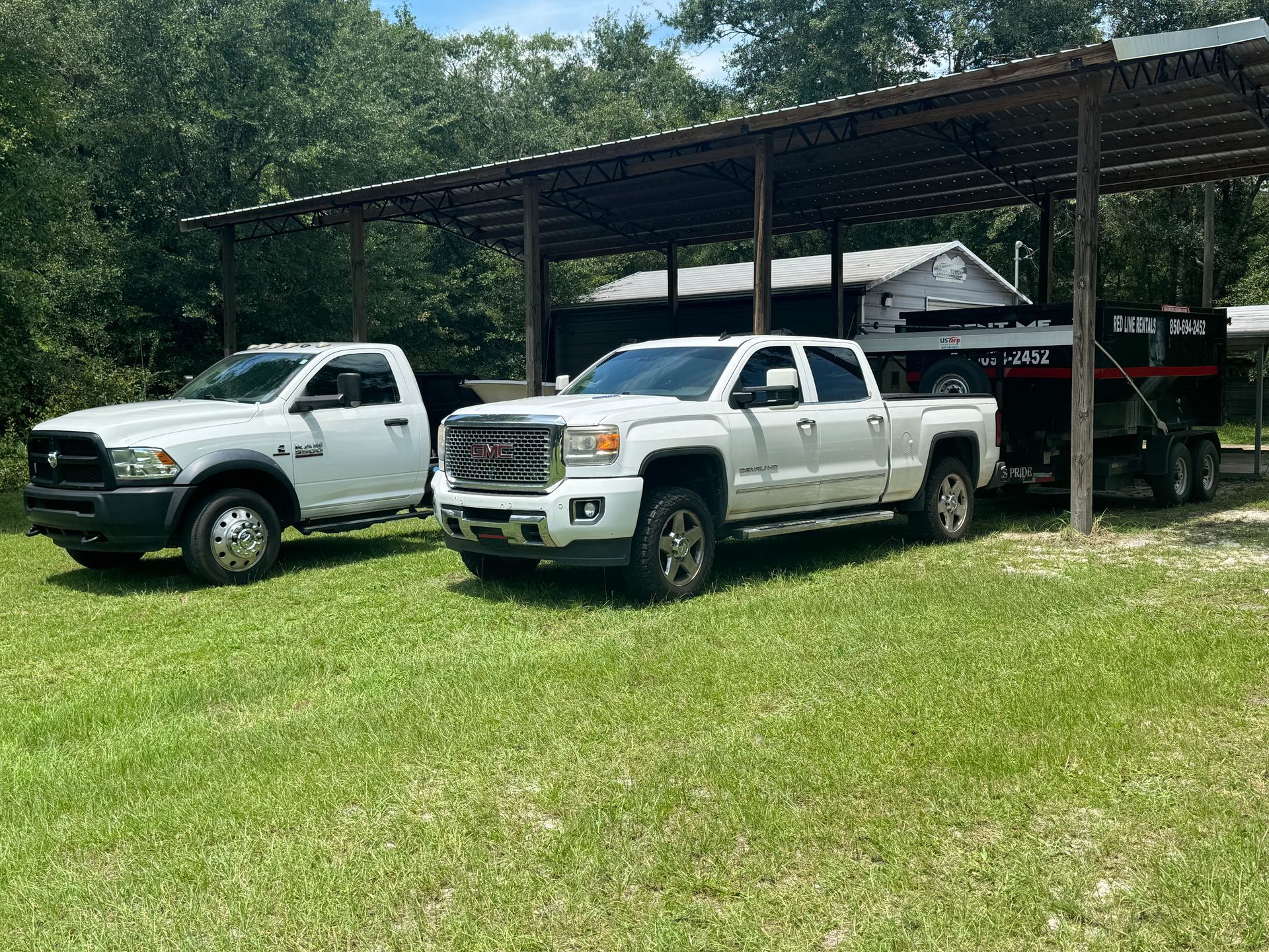 Two white trucks are parked next to each other in a grassy field.
