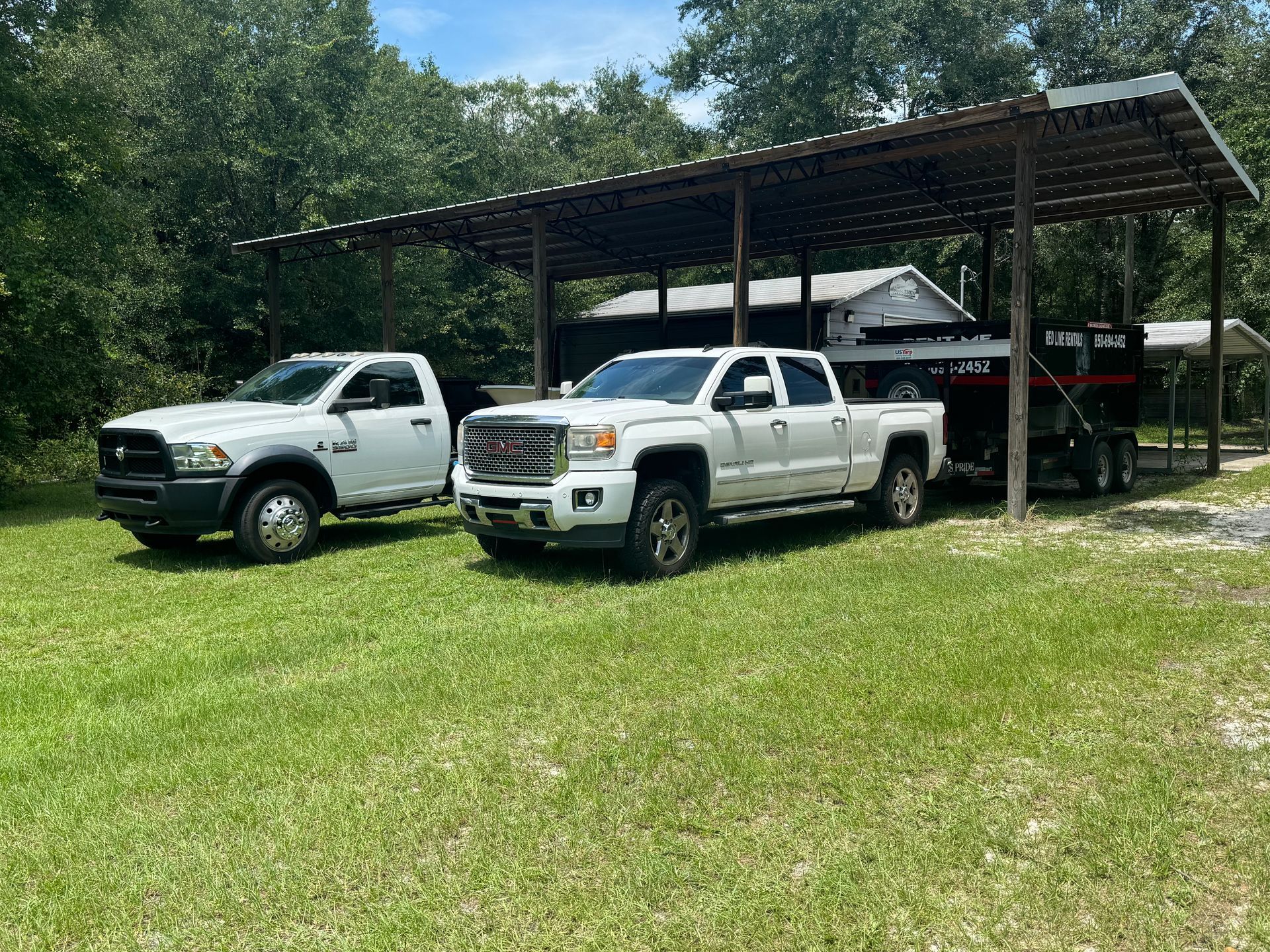 Two white trucks are parked next to each other in a grassy field.