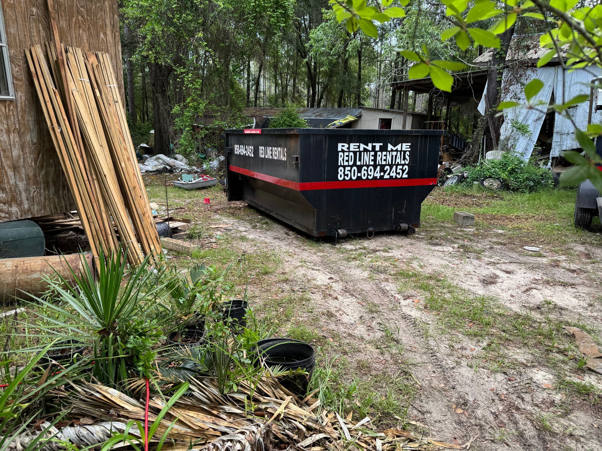 A dumpster is parked in the grass in front of a house.