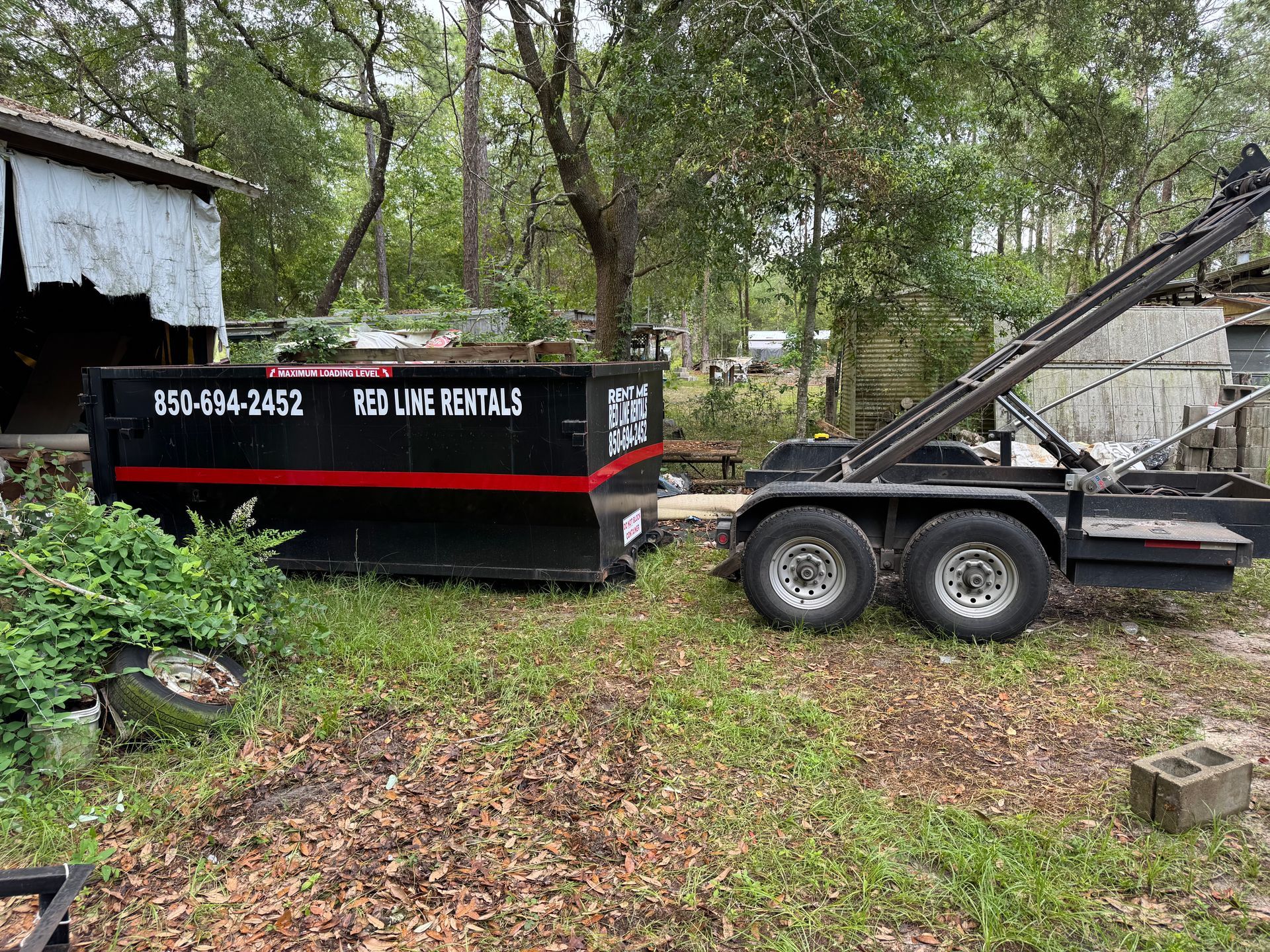 A dumpster is sitting on top of a trailer in a yard.