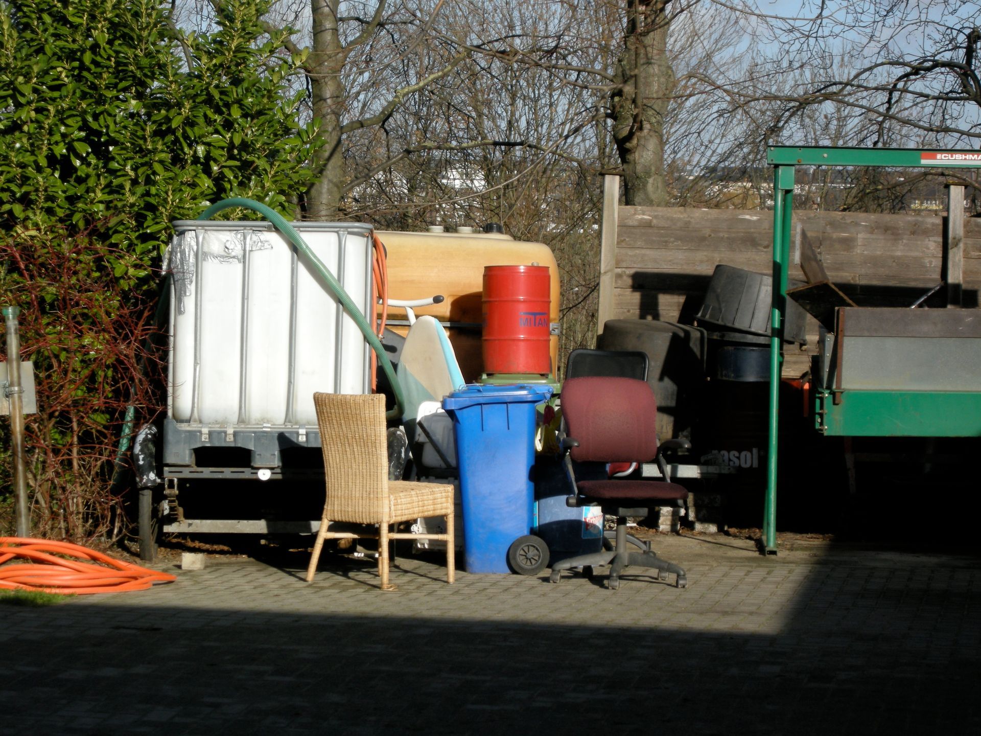 A bunch of trash cans and chairs in a yard