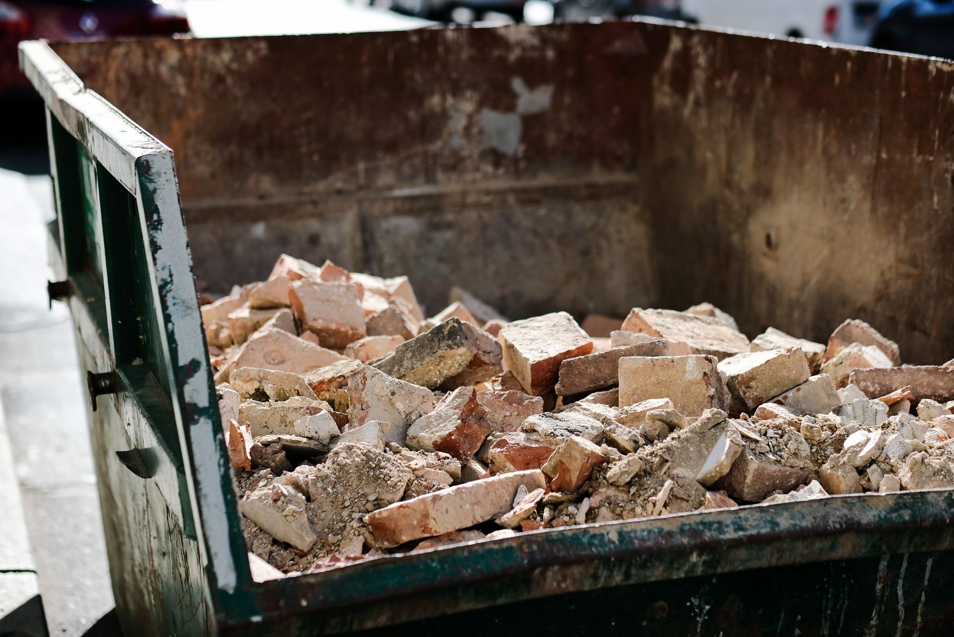 A dumpster filled with bricks is sitting on the side of the road.