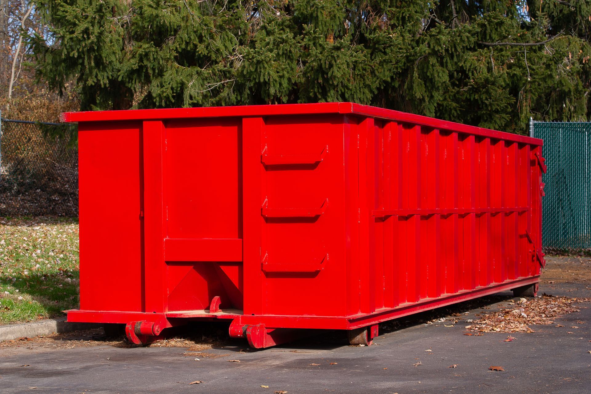 A large red dumpster is parked in a parking lot.