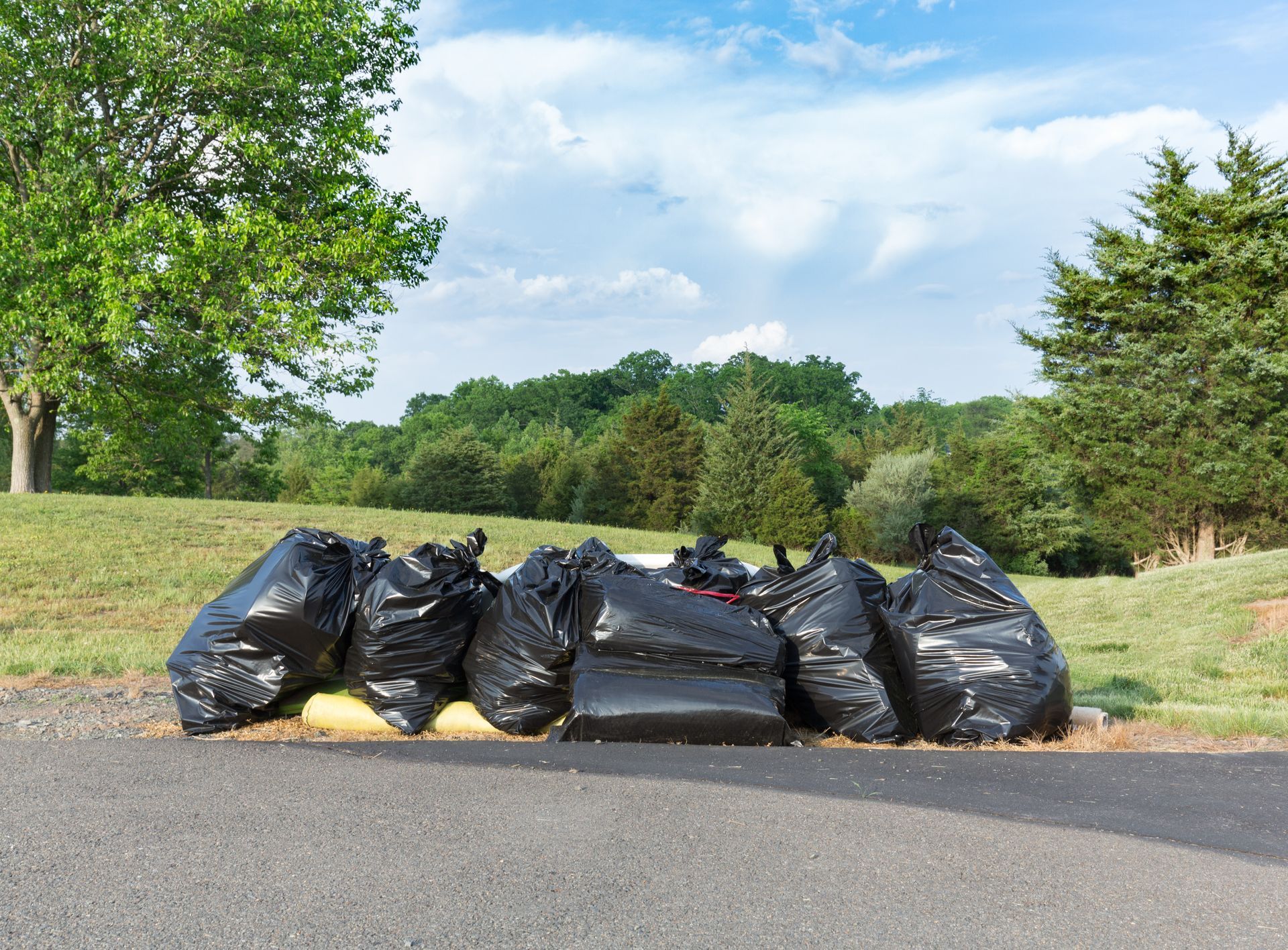 A pile of trash bags sitting on the side of a road.