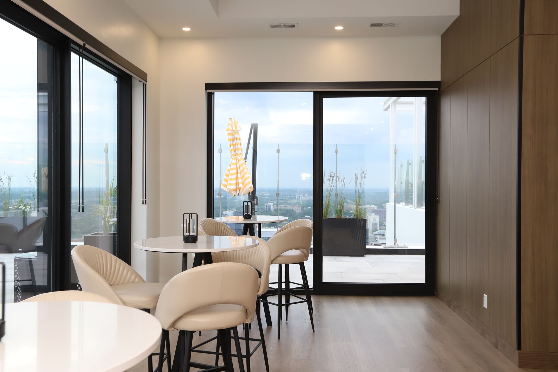 Interior room with tables, chairs, and large windows overlooking a cityscape.