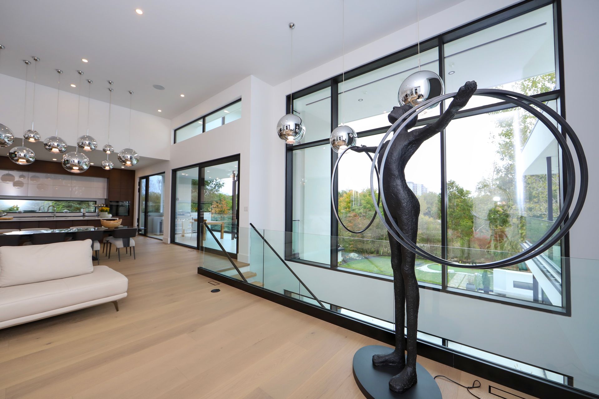 Modern interior with art sculpture, large windows, and light wood floors.