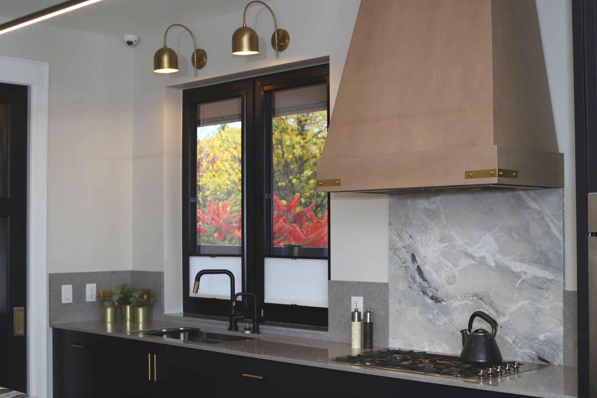 A kitchen with a stove top oven , sink , and two windows.