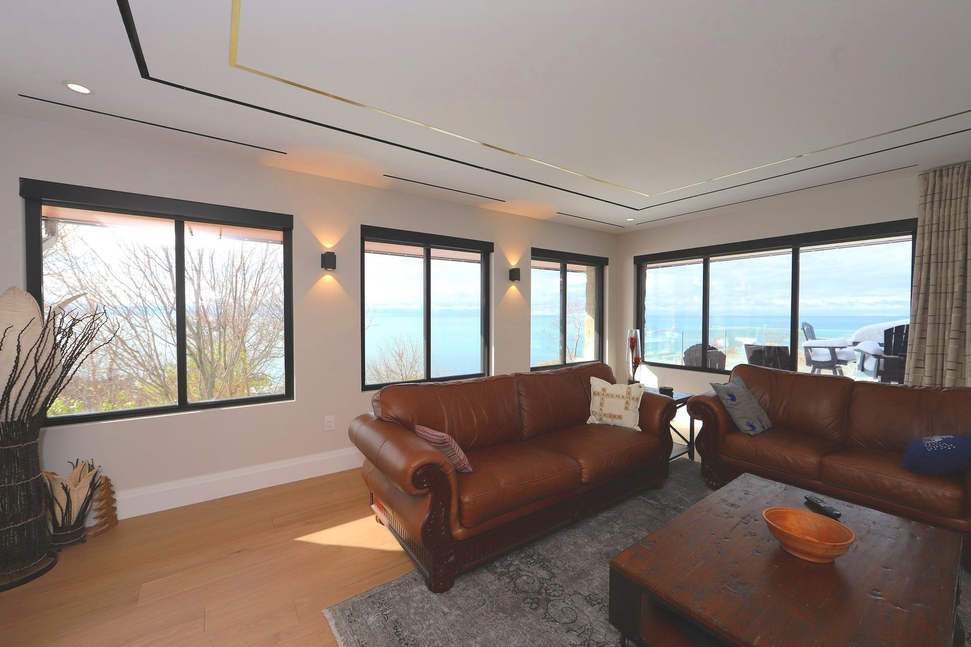 A living room with two couches and a coffee table with a view of the ocean.