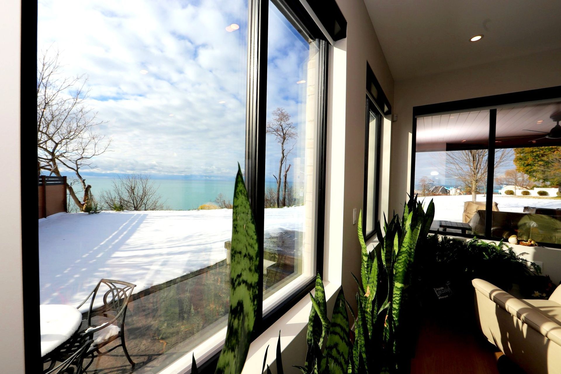 A living room with a lot of windows and a view of the ocean.