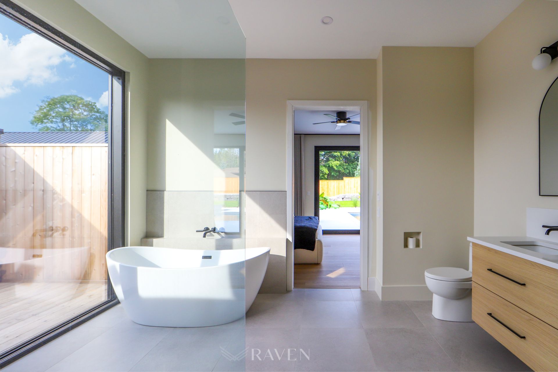 A bathroom with a tub , toilet , sink and large window.