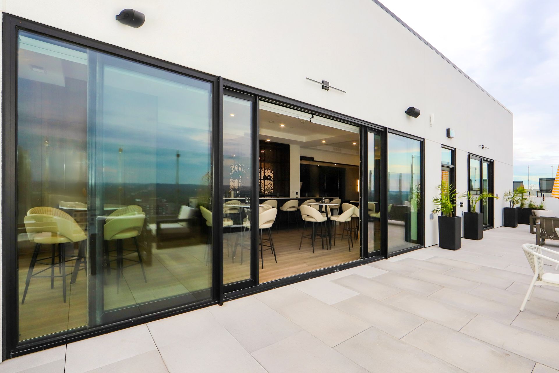 Rooftop bar with glass sliding doors, outdoor seating, and city views.