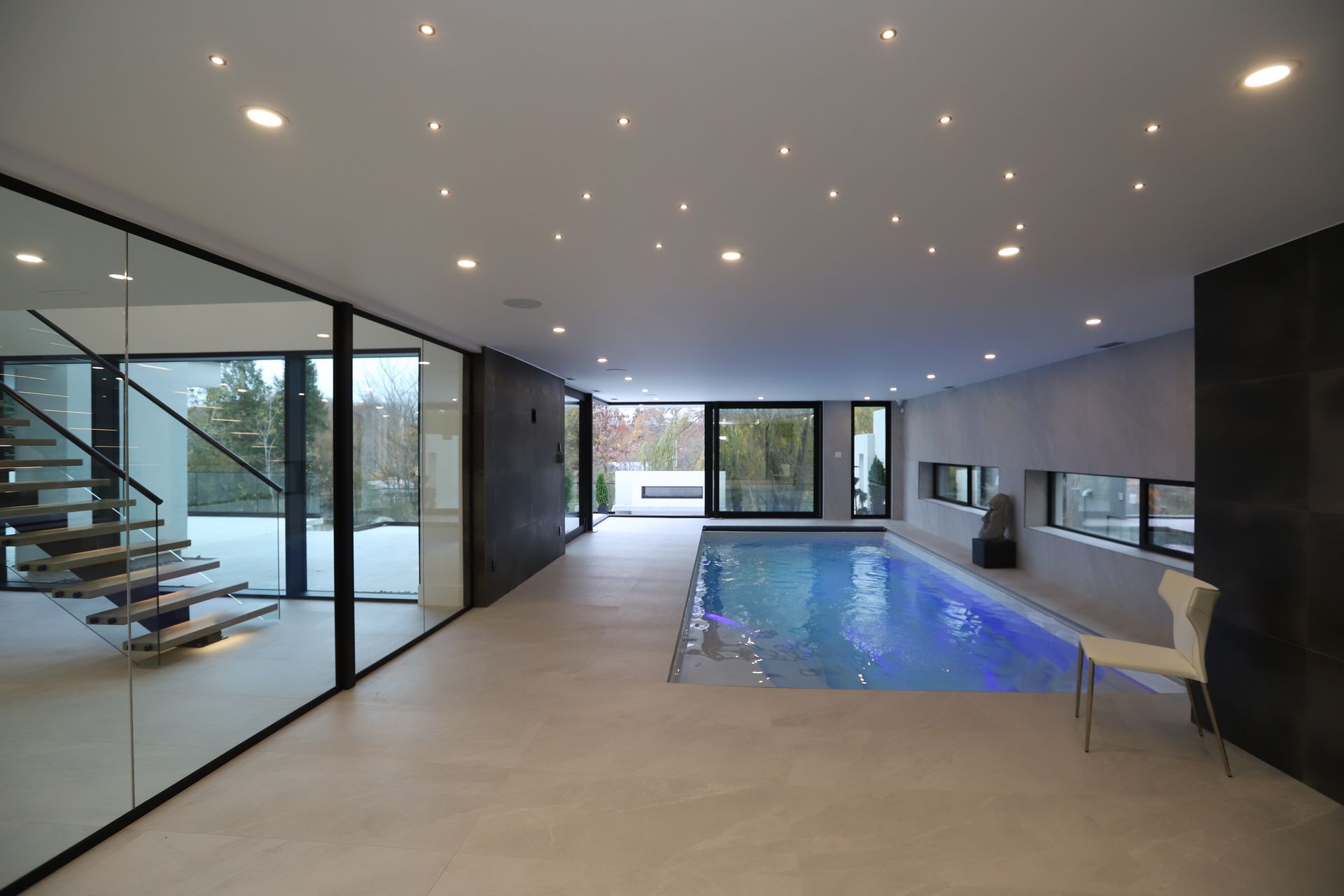 Indoor pool with blue water, surrounded by glass walls and modern architecture.