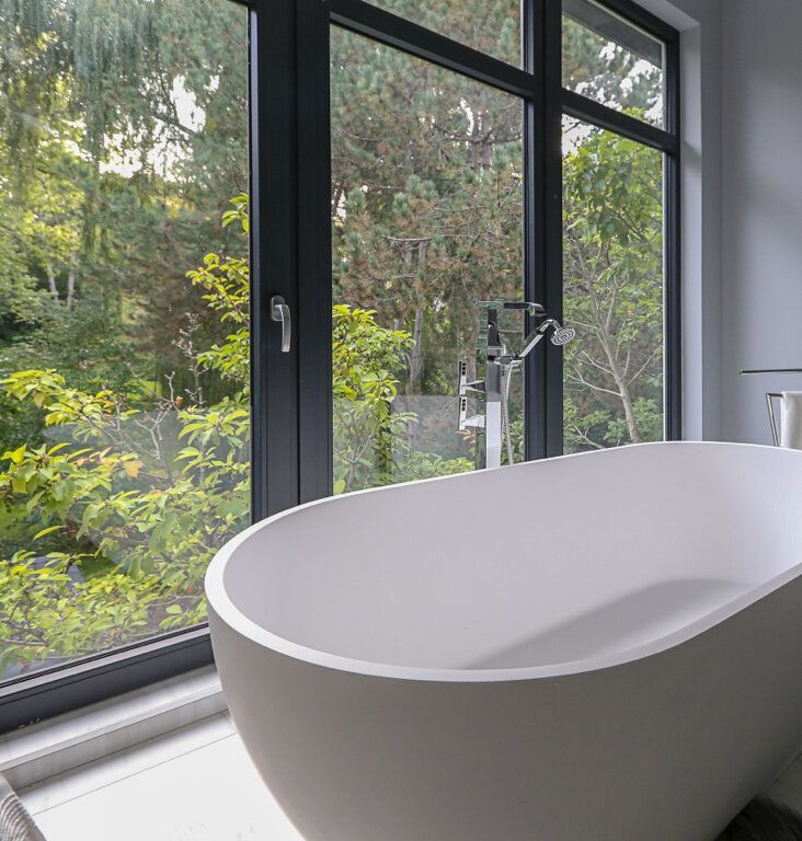 A bathtub is sitting in front of a window in a bathroom.