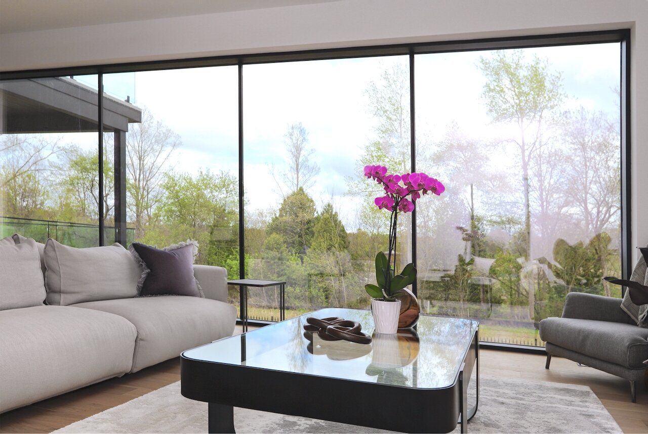 A living room with a couch , chair , coffee table and large windows.