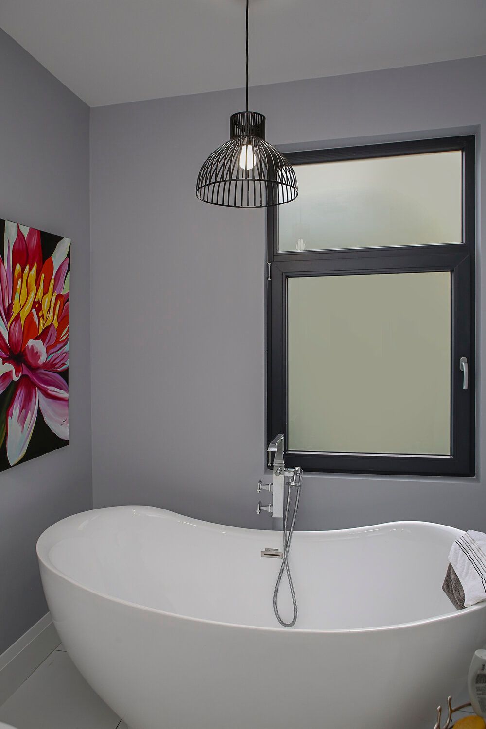 A bathtub in a bathroom with a picture of a flower on the wall.