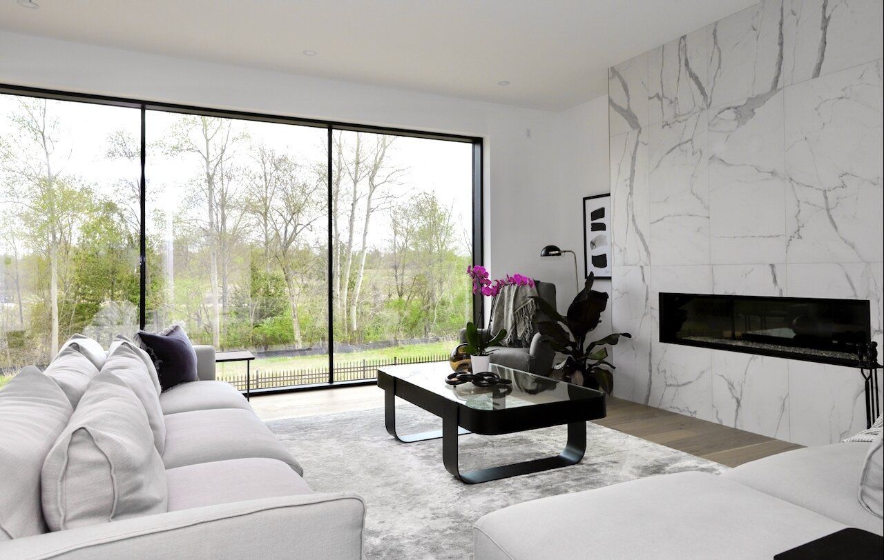 A living room with a couch , coffee table , fireplace and large windows.