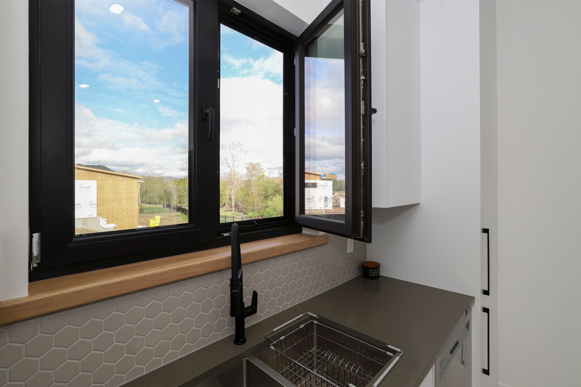 A kitchen with a sink , faucet , and two windows.