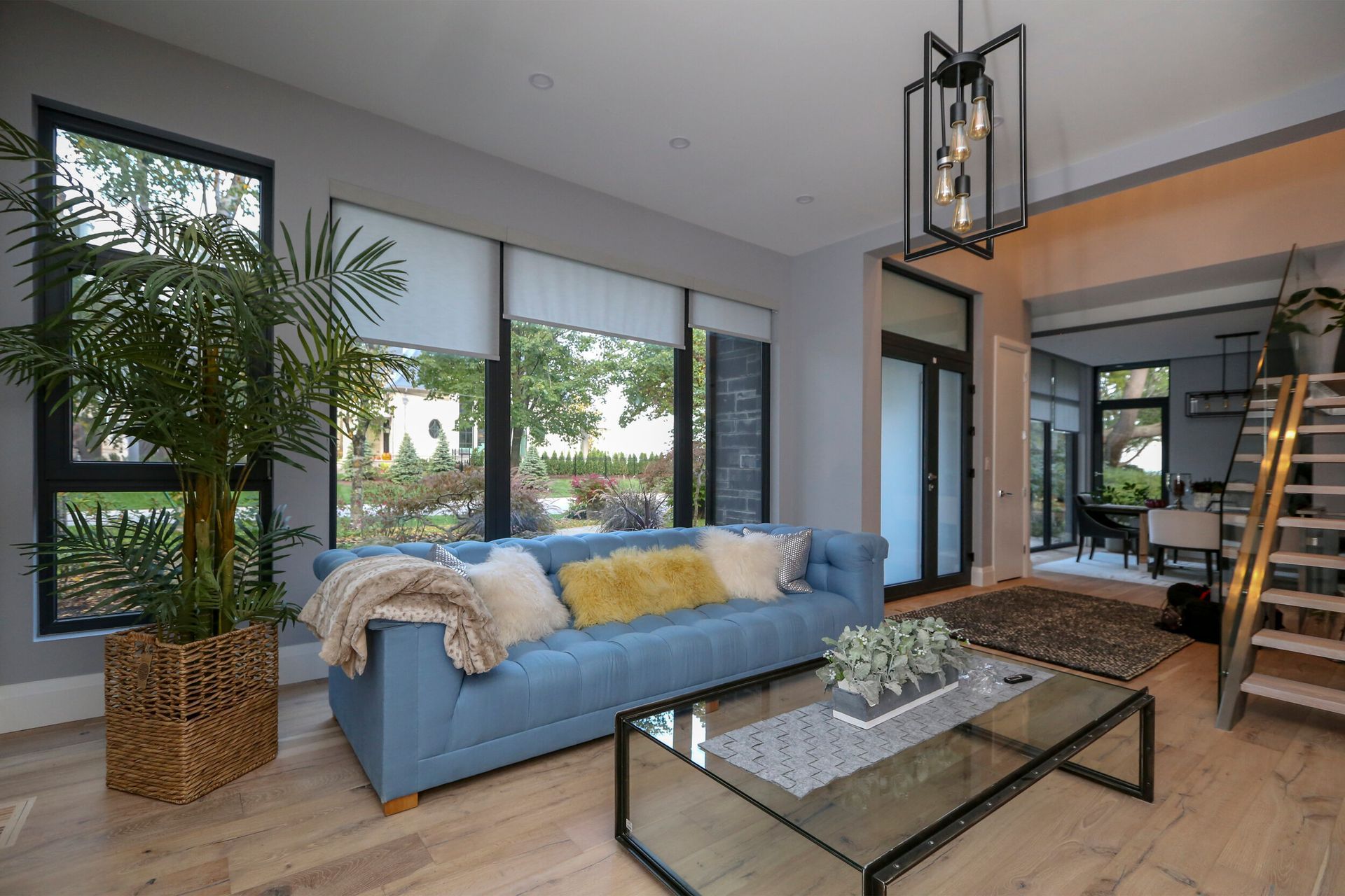 A living room with a blue couch and a glass coffee table.