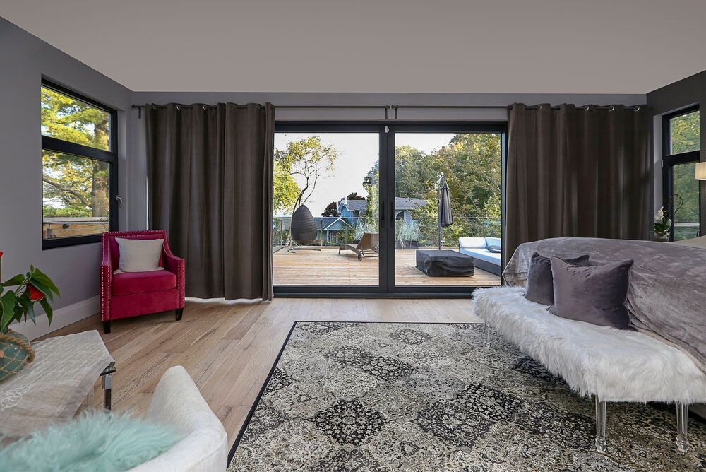 A living room with a couch , chair , rug and sliding glass doors.