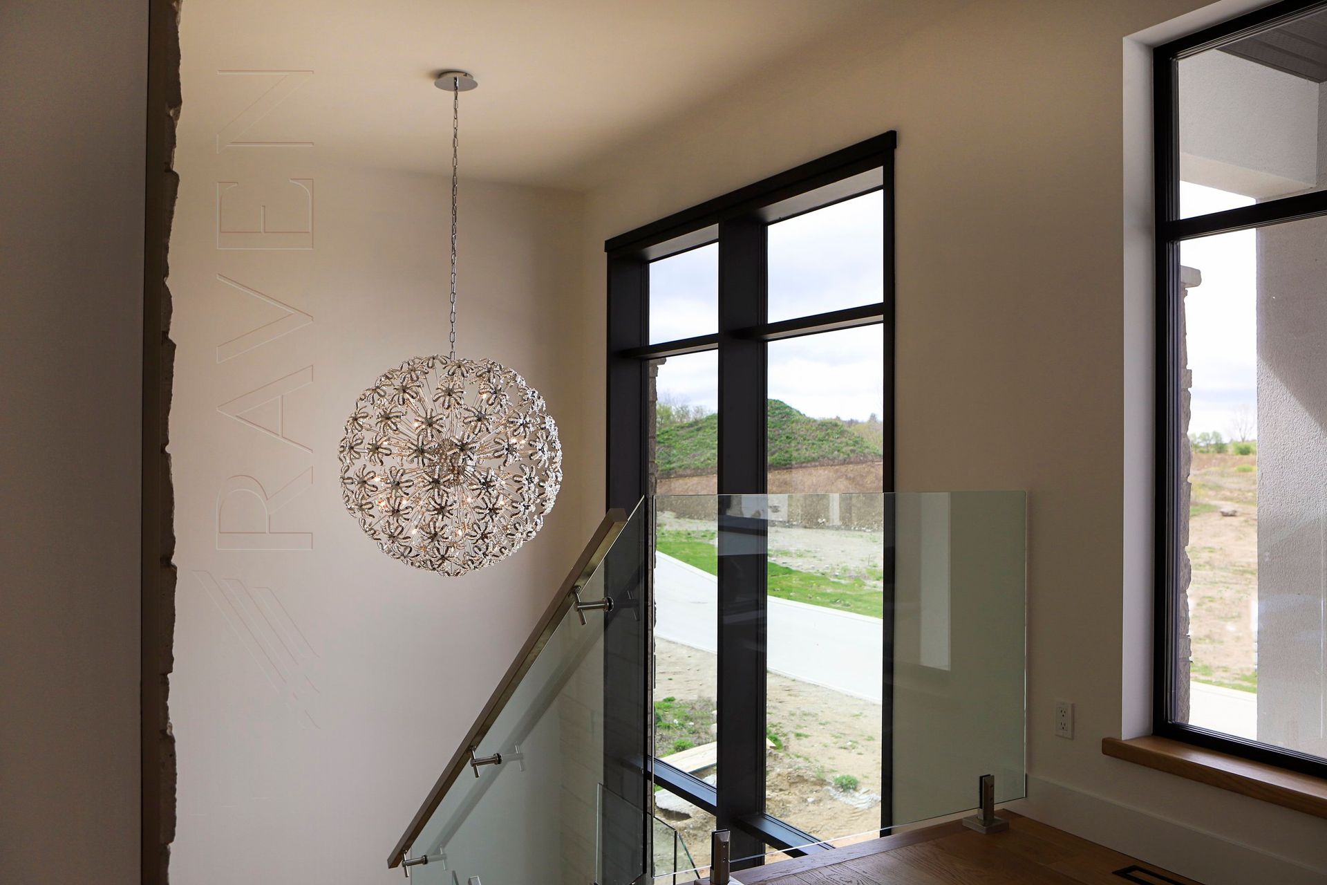A staircase with a glass railing and a chandelier hanging from the ceiling.