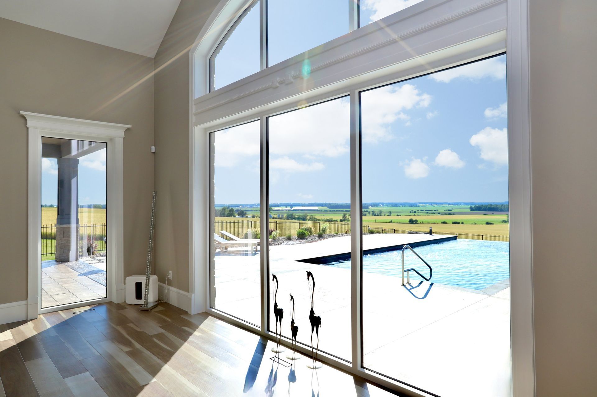 An empty room with a large window and a view of a swimming pool.