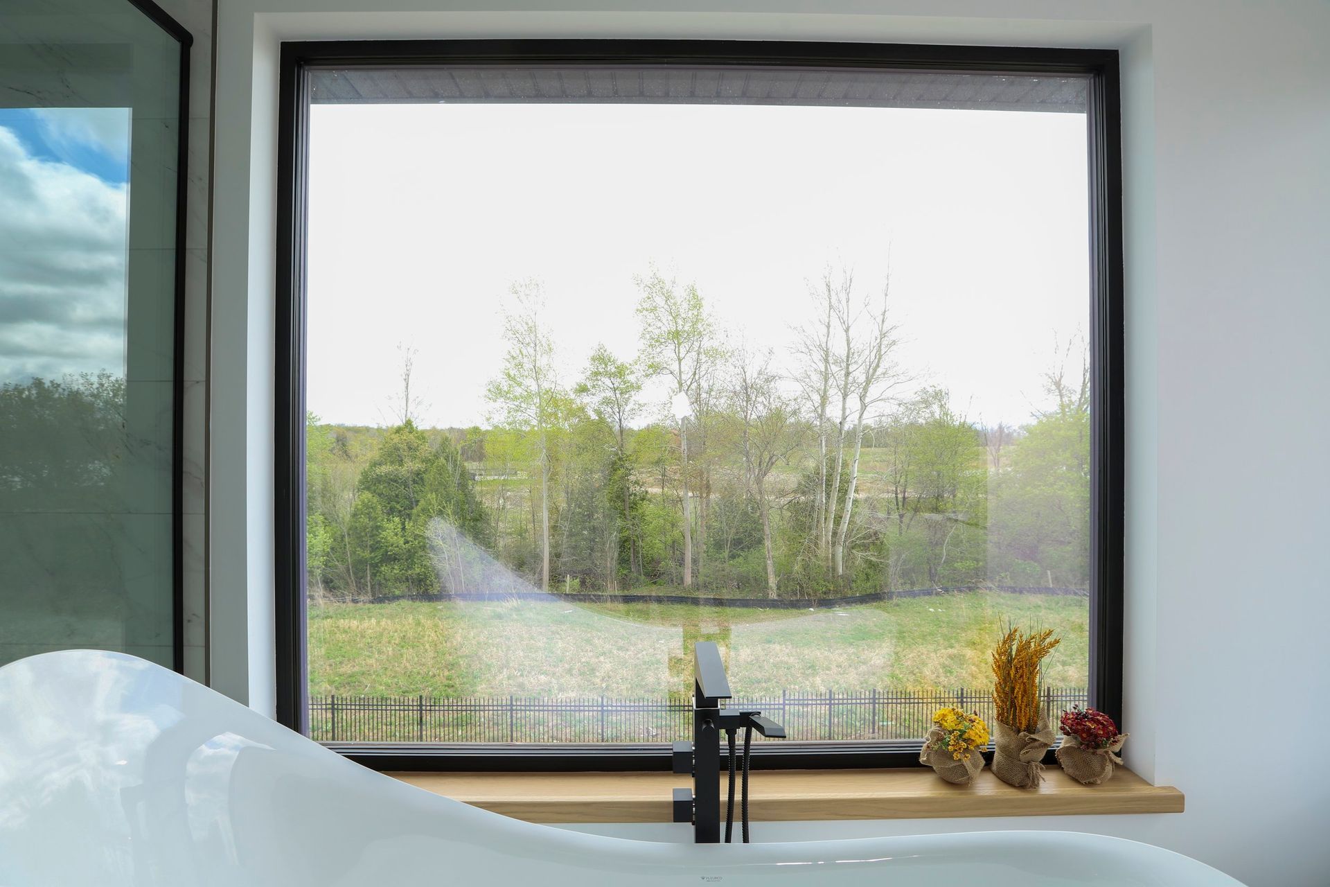 A bathroom with a bathtub and a large window with a view of a field.