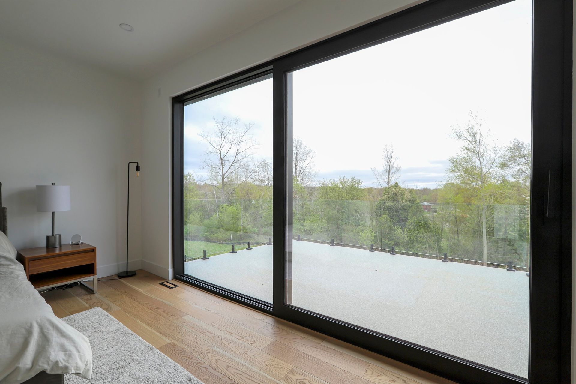 A bedroom with a large sliding glass door leading to a balcony.