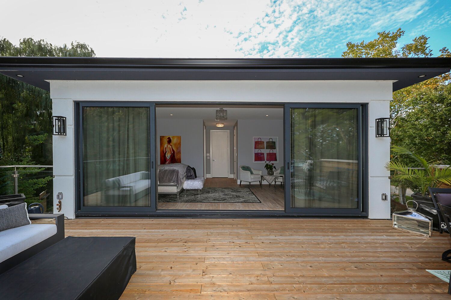 A modern house with sliding glass doors and a wooden deck.