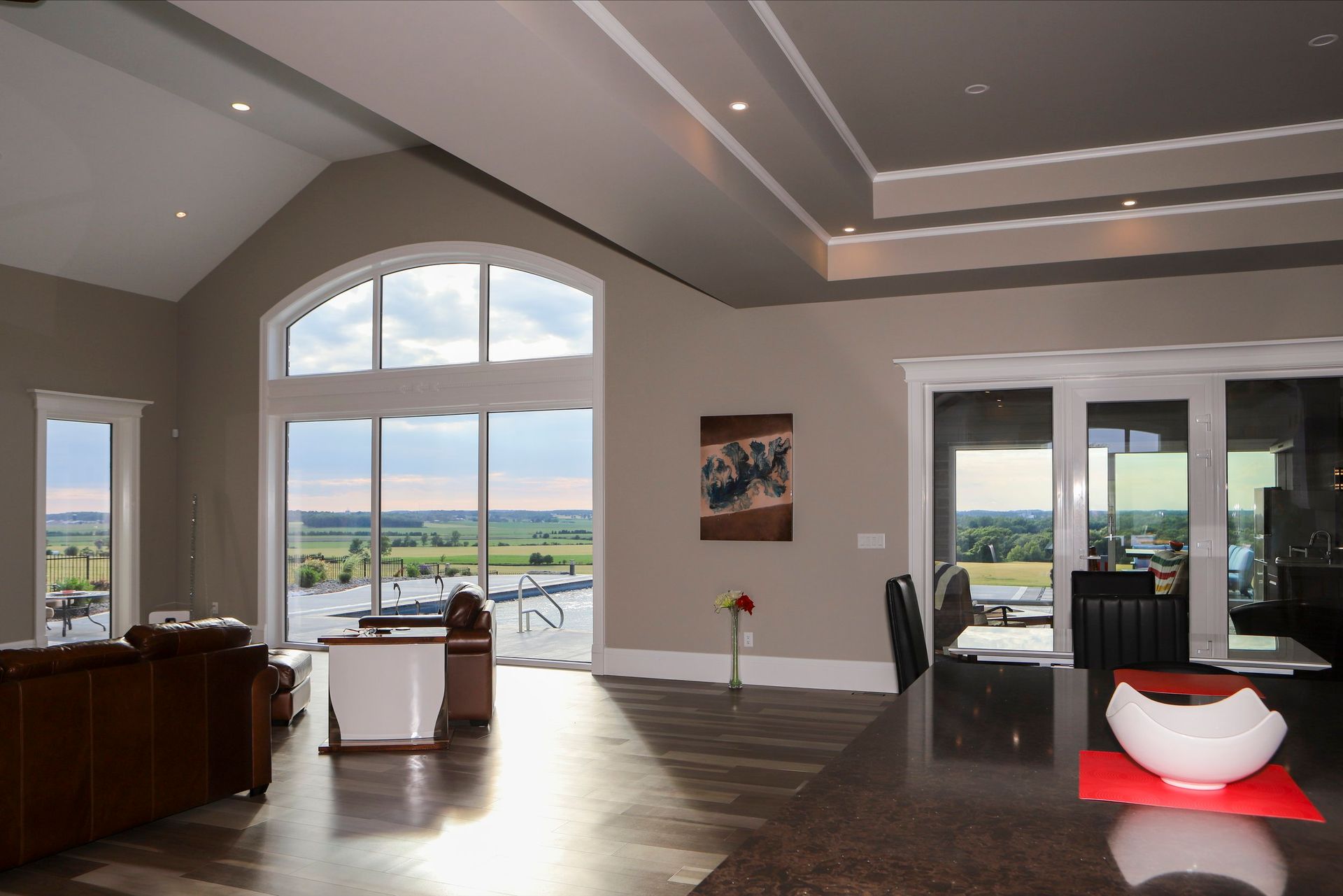A living room with a lot of windows and a painting on the wall