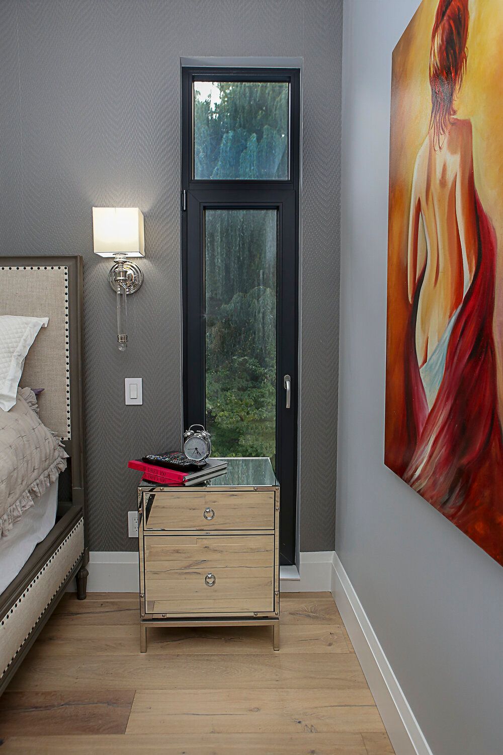 A bedroom with a bed , nightstand , and a painting on the wall.