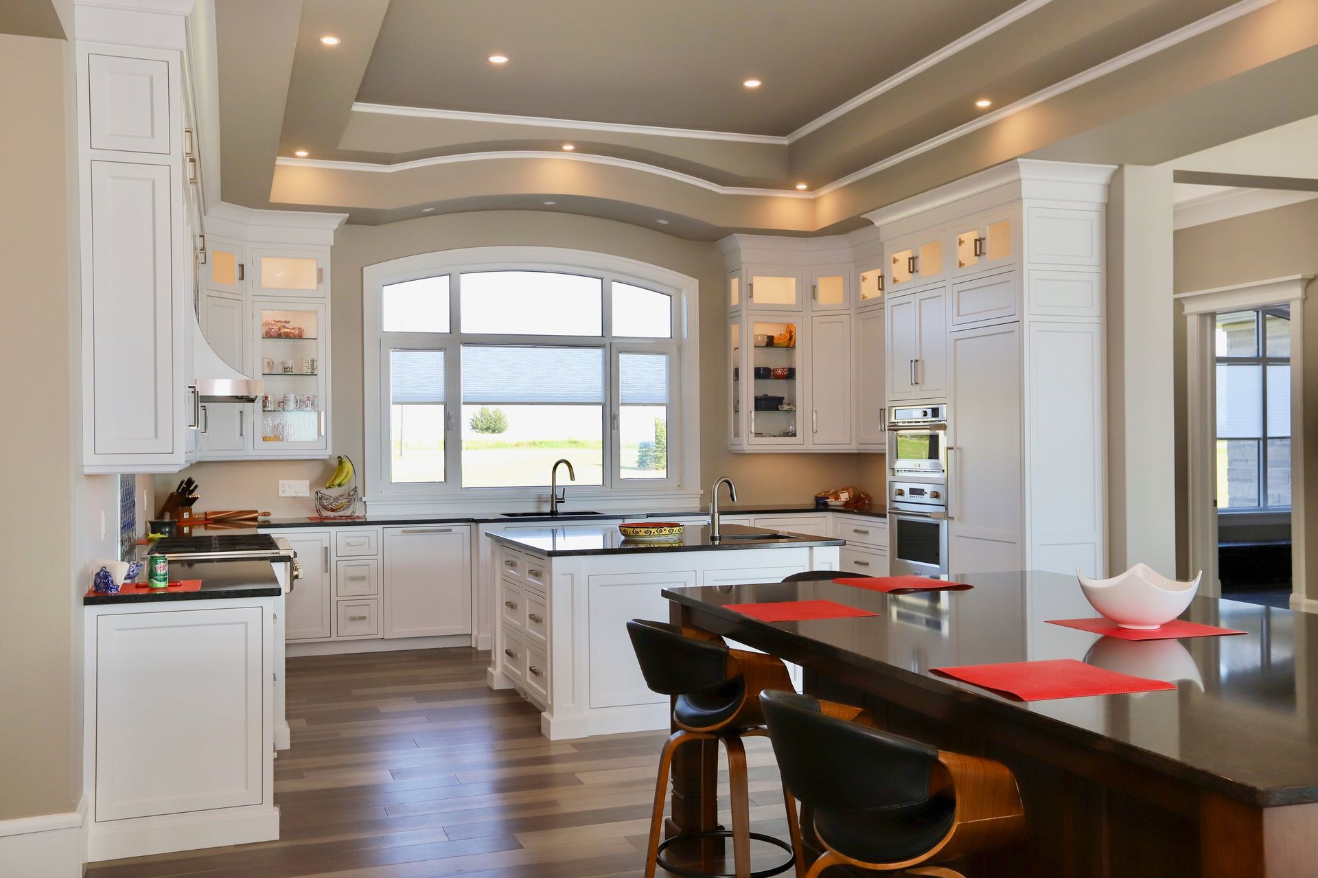 A kitchen with white cabinets , black counter tops , and a large island.