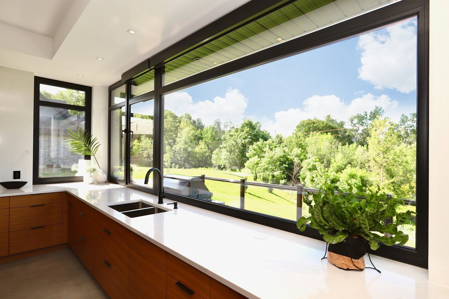 A kitchen with a large window overlooking a lush green field.