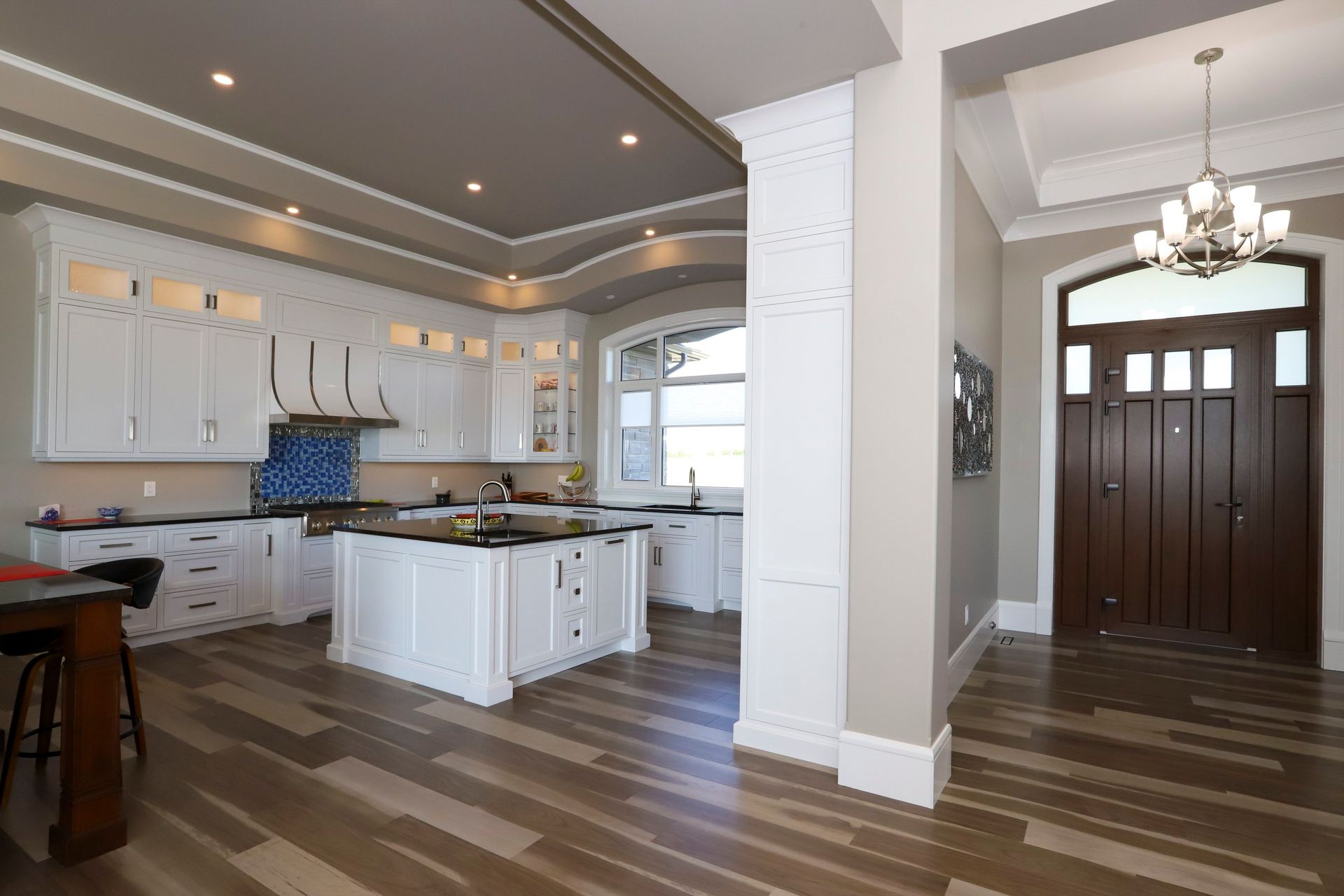 A large kitchen with white cabinets and a wooden floor.