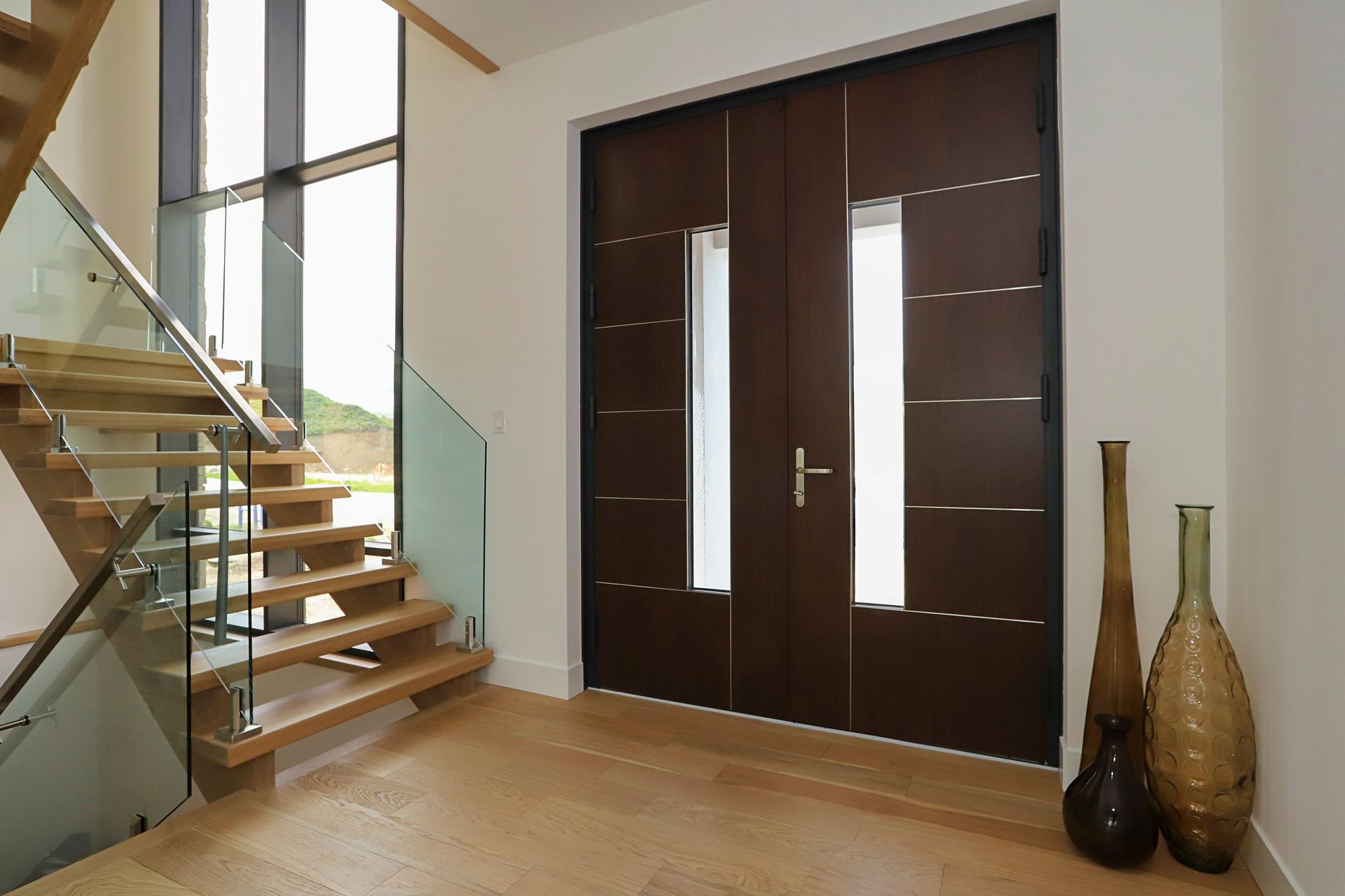 A hallway with stairs and two vases on the floor