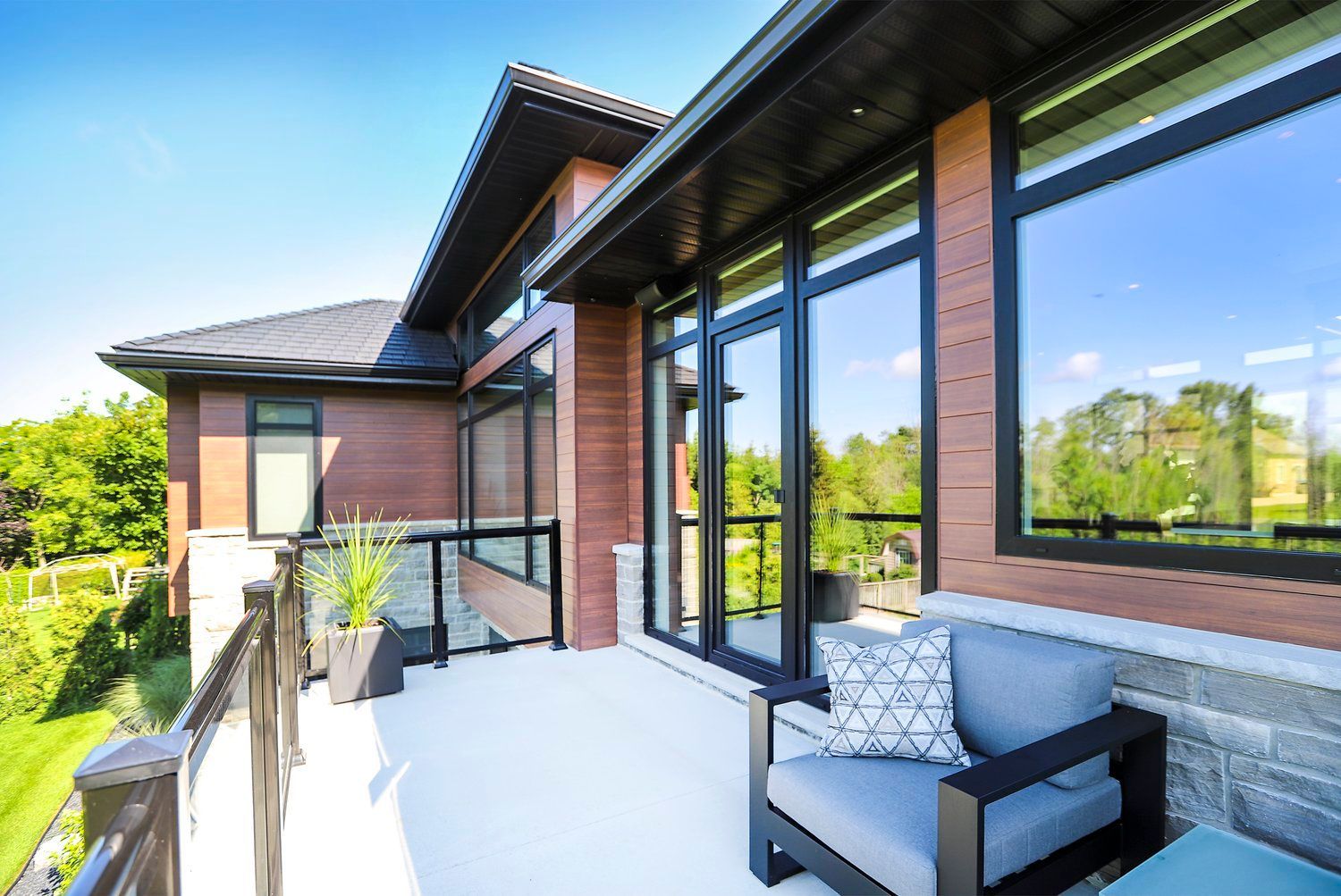 A balcony with a chair and a table in front of a large house.